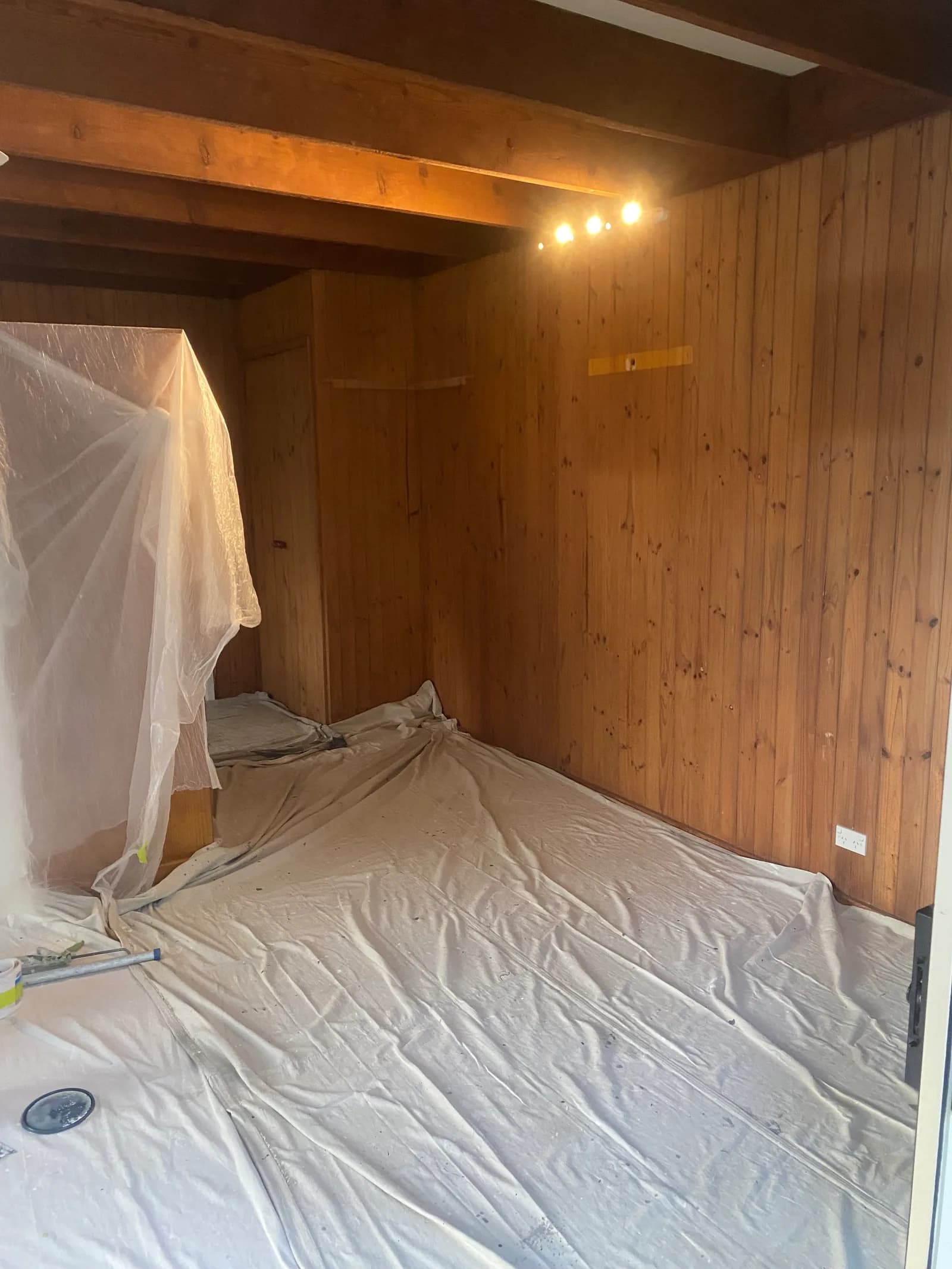 Sydney interior repaint prepared for painting, with floors sheeted and furniture masked beneath a timber ceiling