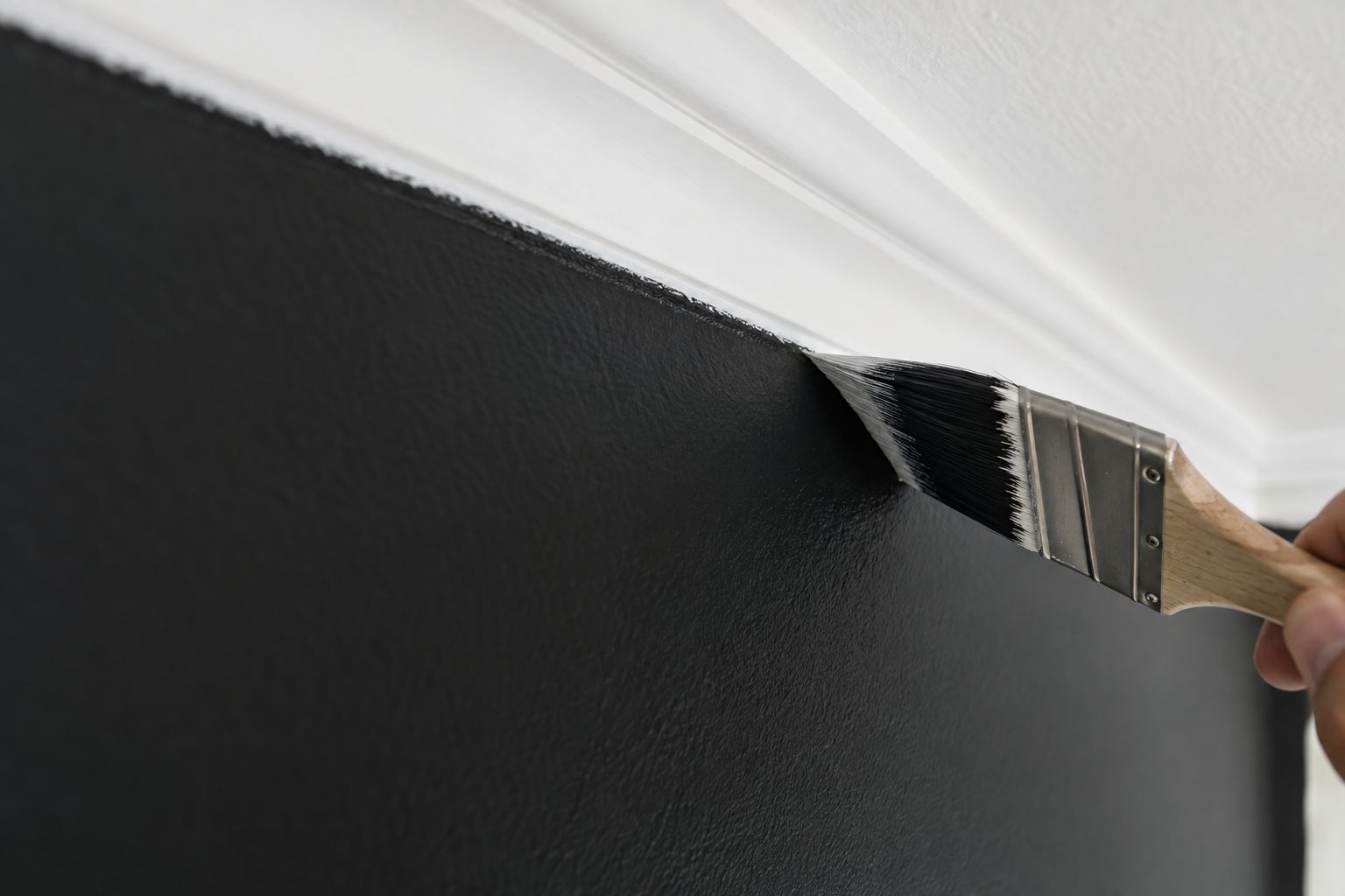 Brush cutting a crisp line between a charcoal wall and white cornice